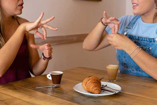 young-women-drinking-coffee-speaking-sign-language young-women